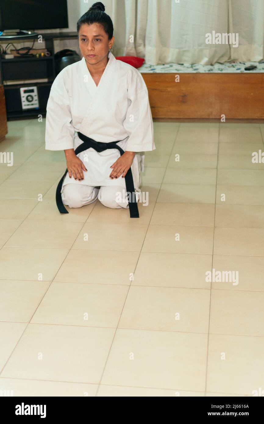 Latina female athlete in traditional uniform practicing karate at home