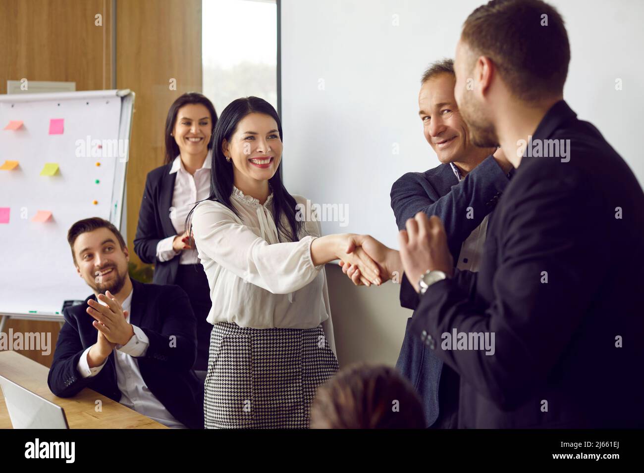 Man and woman shake hands and smile as they greet each other at a business meeting Stock Photo