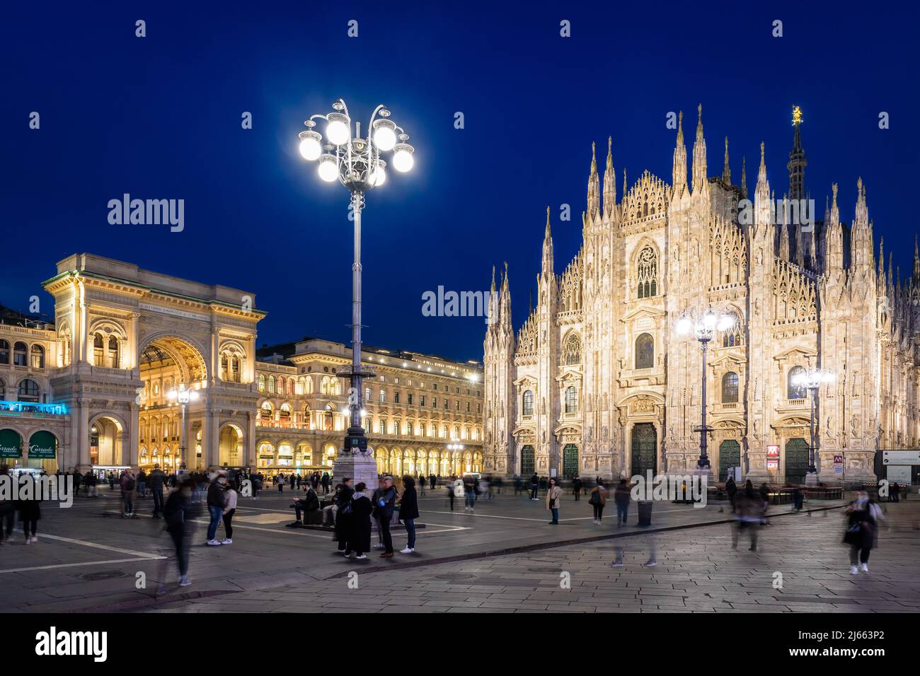 People enjoy the Piazza del Duomo, dominated by the facade of the cathedral and the Vittorio Emanuele II gallery's entrance at night in Milan, Italy. Stock Photo