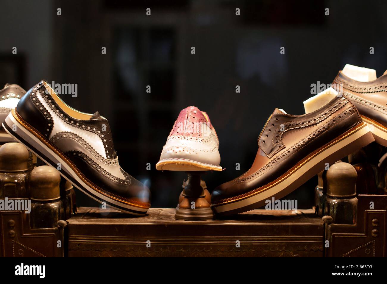 Brogue shoes with rubber soles are standing in a window display of a shoemaker workshop at night. They are standing on a vintage shoe care box. Stock Photo