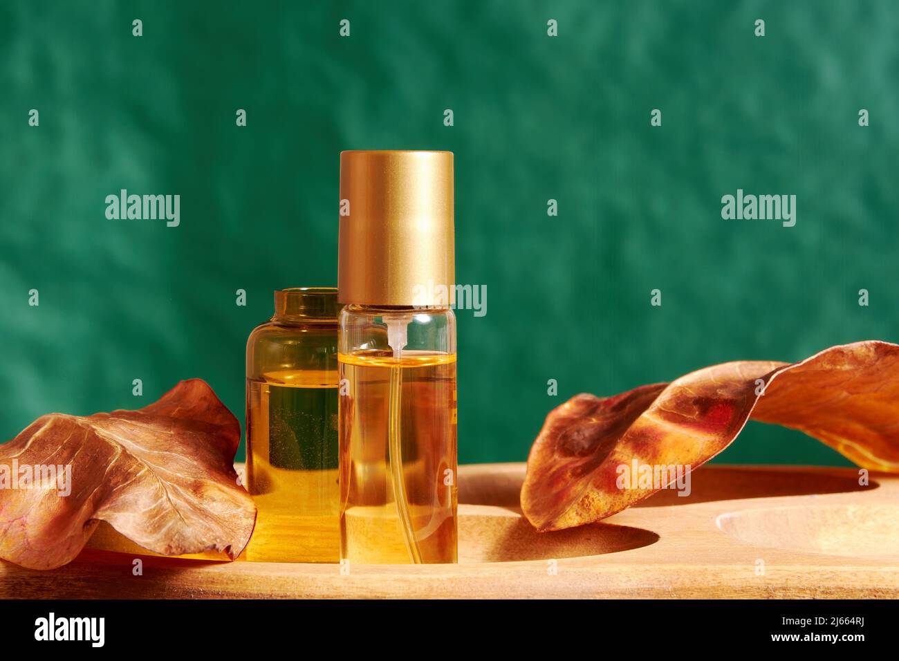 Flowers perfume vial on the stand with skin tonic and natural leaves. Cosmetics and fashion and bodycare backgrounds Stock Photo