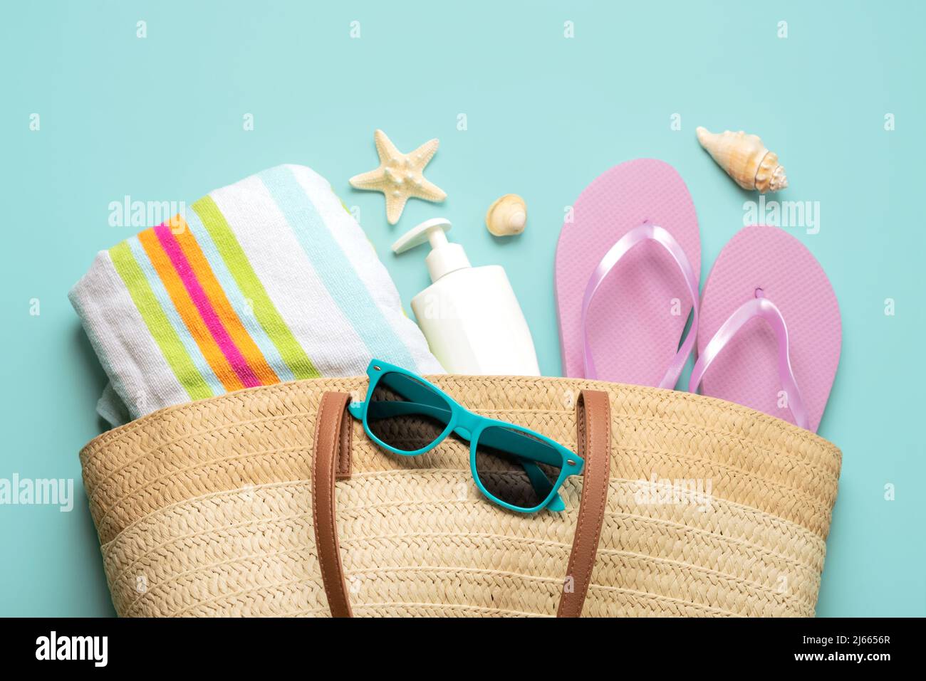 Summer holiday concept.Top view of beach bag with flip flops,beach towel,sunglasses,sea shells and starfish over blue background. Stock Photo