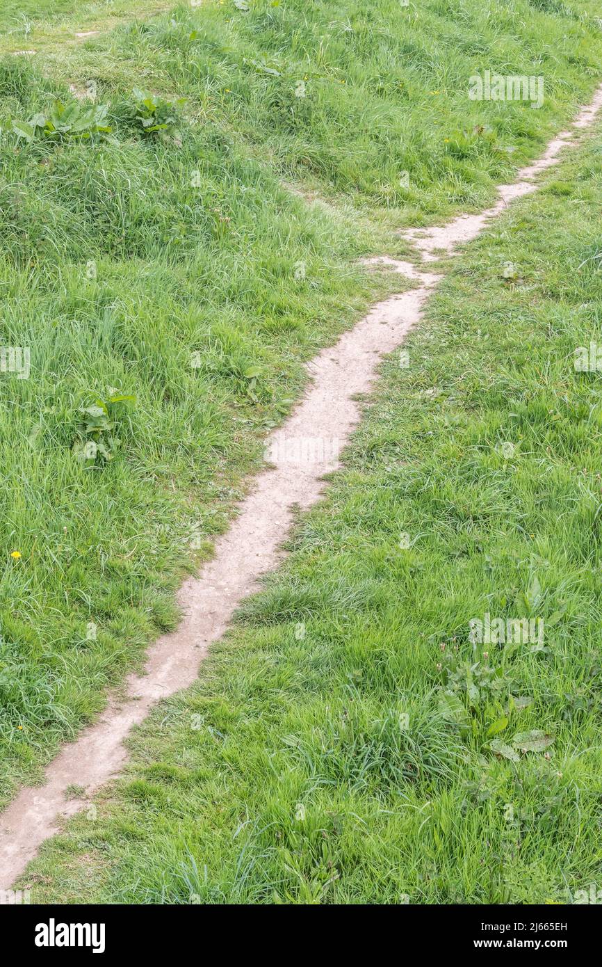 Beaten, heavily trodden, footpath alongside a river bank in UK. For stretching into the distance, career path, taking a hard line, bare earth. Stock Photo
