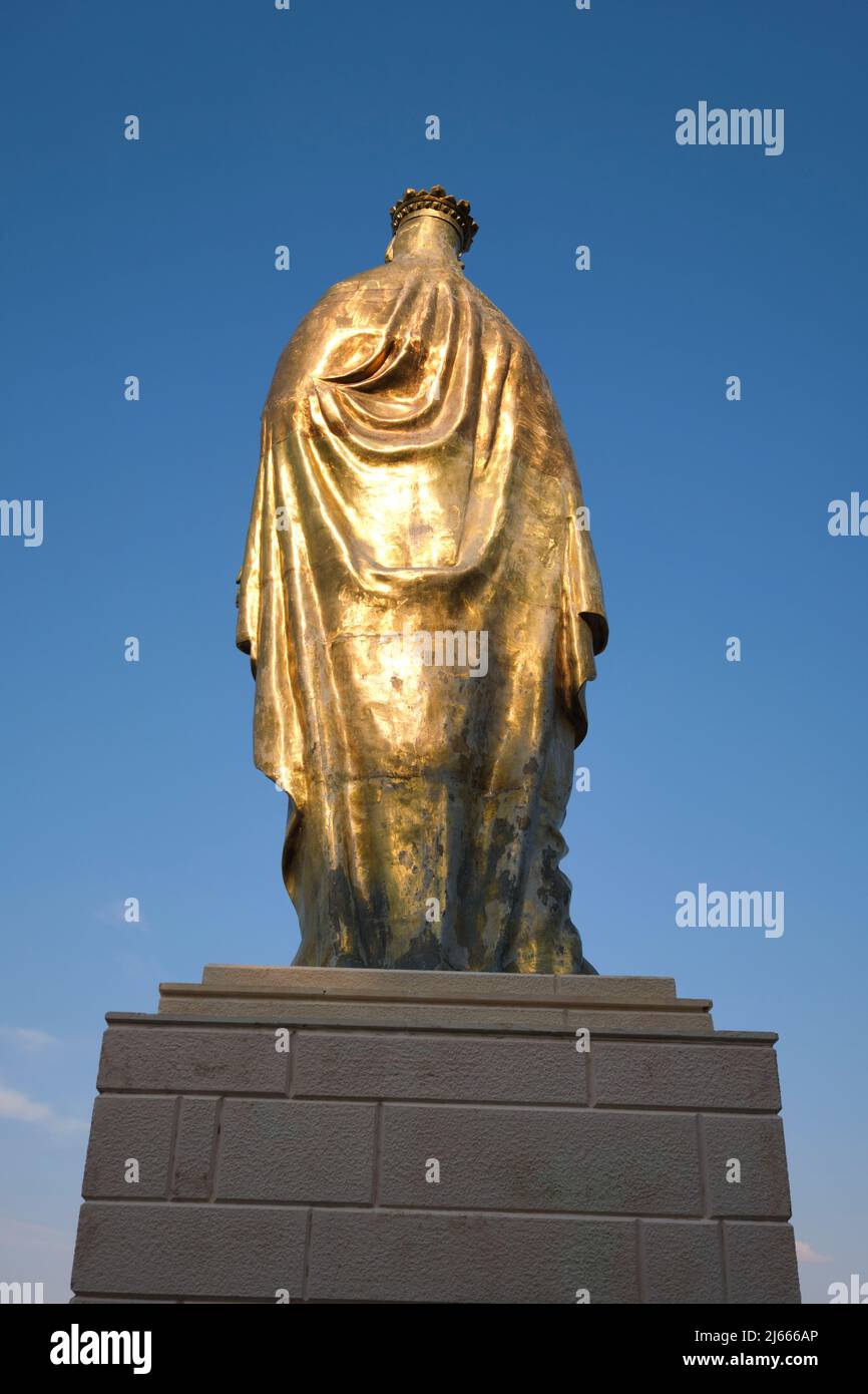 Looking up at at the back of a large, giant, huge gold sculpture of the Virgin Mary. At the