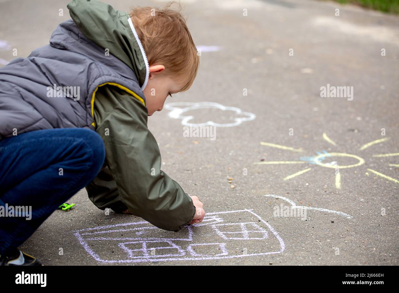 A boy draws a house with chalk on the asphalt Stock Photo - Alamy