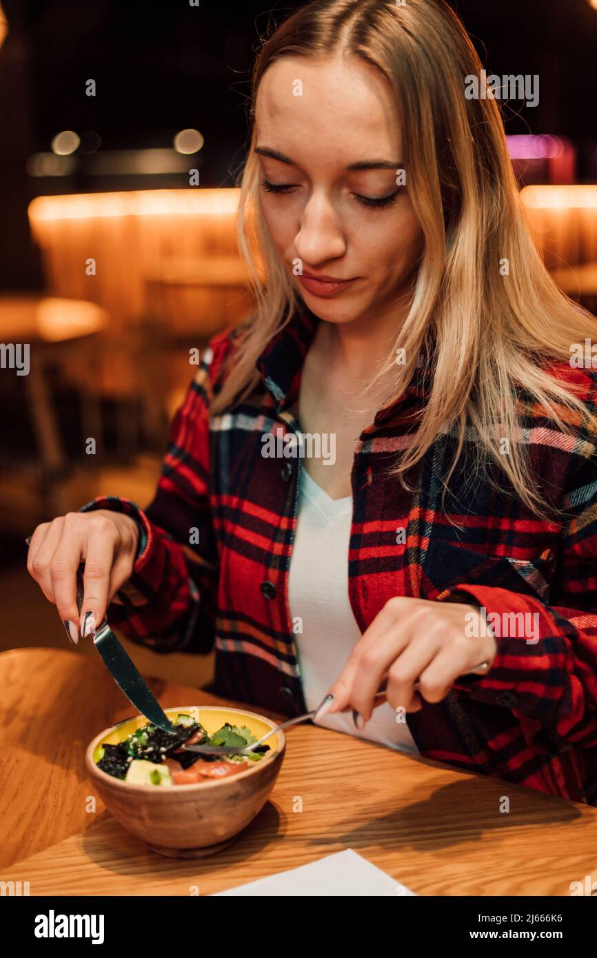 A young girl is going to eat a salad in a restaurant with a fork and