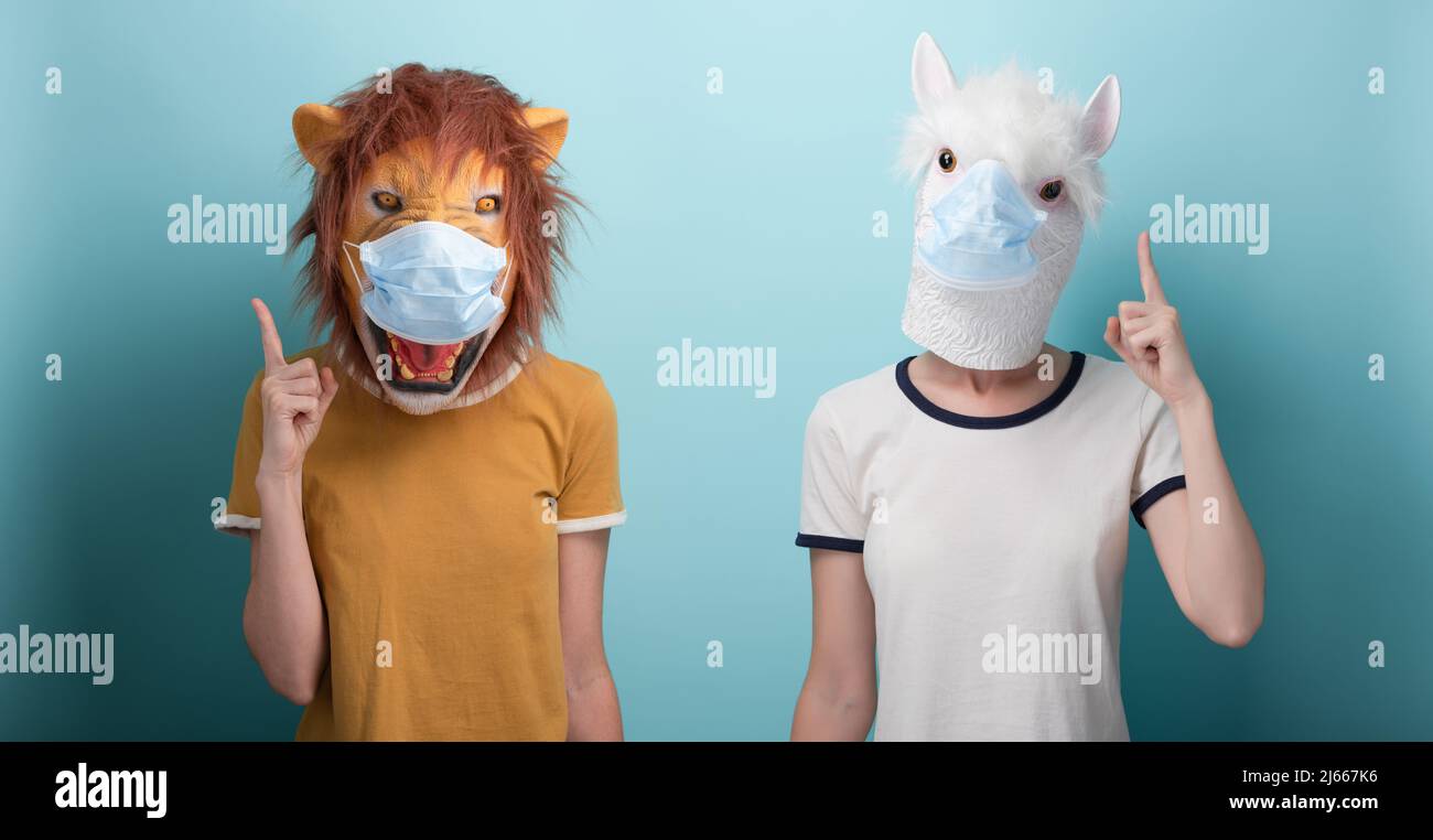 Young woman wearing lion and alpaca and protection medical mask pointing up with index finger, capture the attention or warning advice Stock Photo