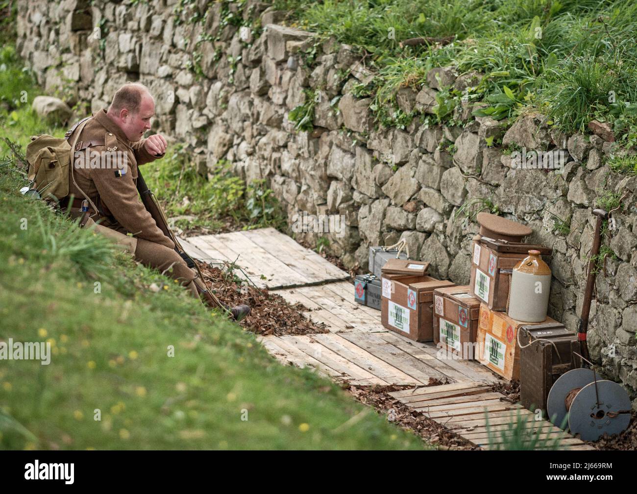 A re-enactor soldier from the WW1 Essex Regiment rests by a trench ammunition dump at the No Man's Land Event at Bodrhyddan Hall, Wales Stock Photo