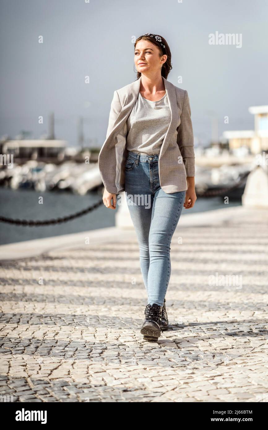 A portrait of a young confident woman walking in the city by marina Stock Photo