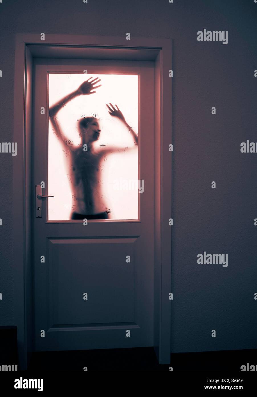 Gruselige Silhouette eines jungen Erwachsenen im Gegenlicht hinter einer verschlossenen Glastuere, 14 Jahre, Angst, Verzweiflung, Oberoesterreich Stock Photo
