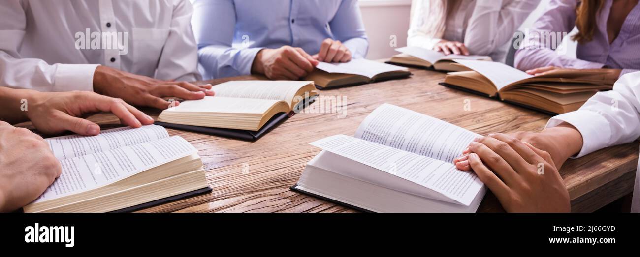 Group Of People Reading Bible On Wooden Desk Stock Photo