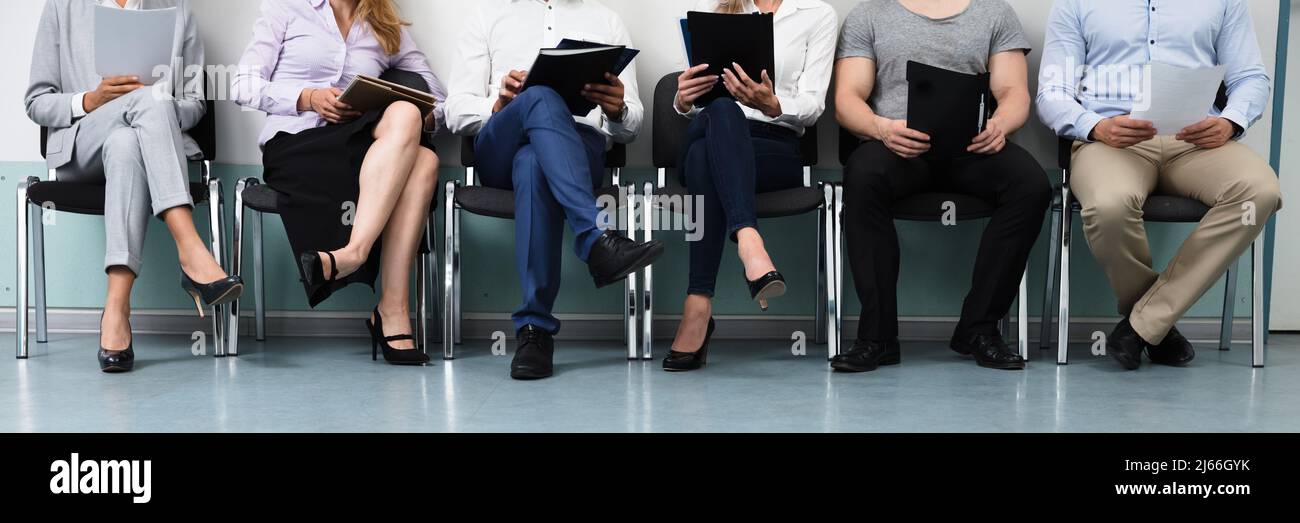 Row Of Candidates Sitting On Chair For Job Interview Stock Photo