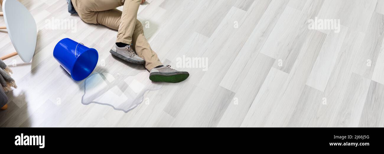 Mature Man Falling On Wet Floor In Front Spilled Bucket Of Water At Home Stock Photo