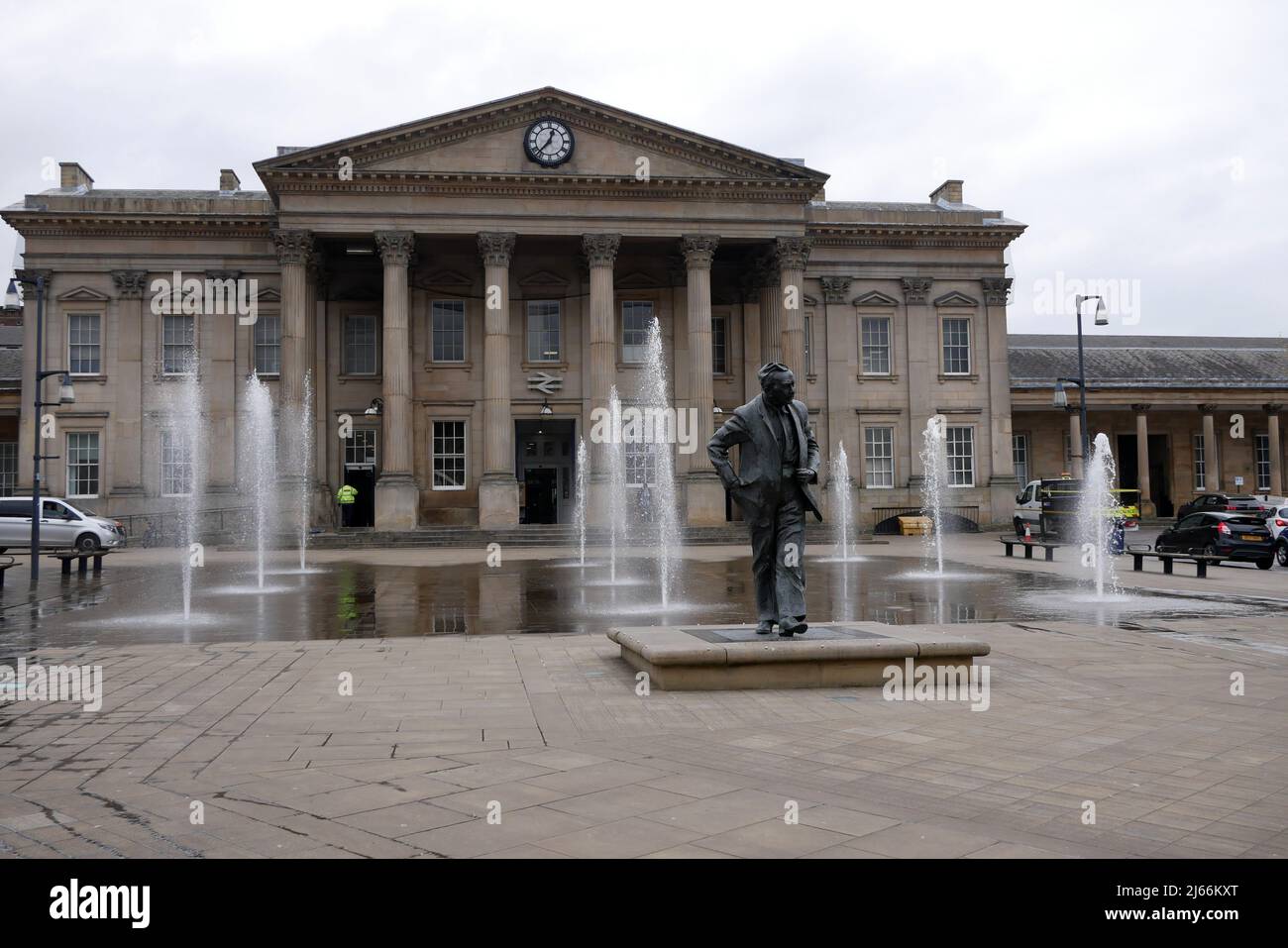 Water fountains and statue of Harold Wilson ex prime minister outside stone built Victorian railway station in Huddersfield Yorkshire England Stock Photo