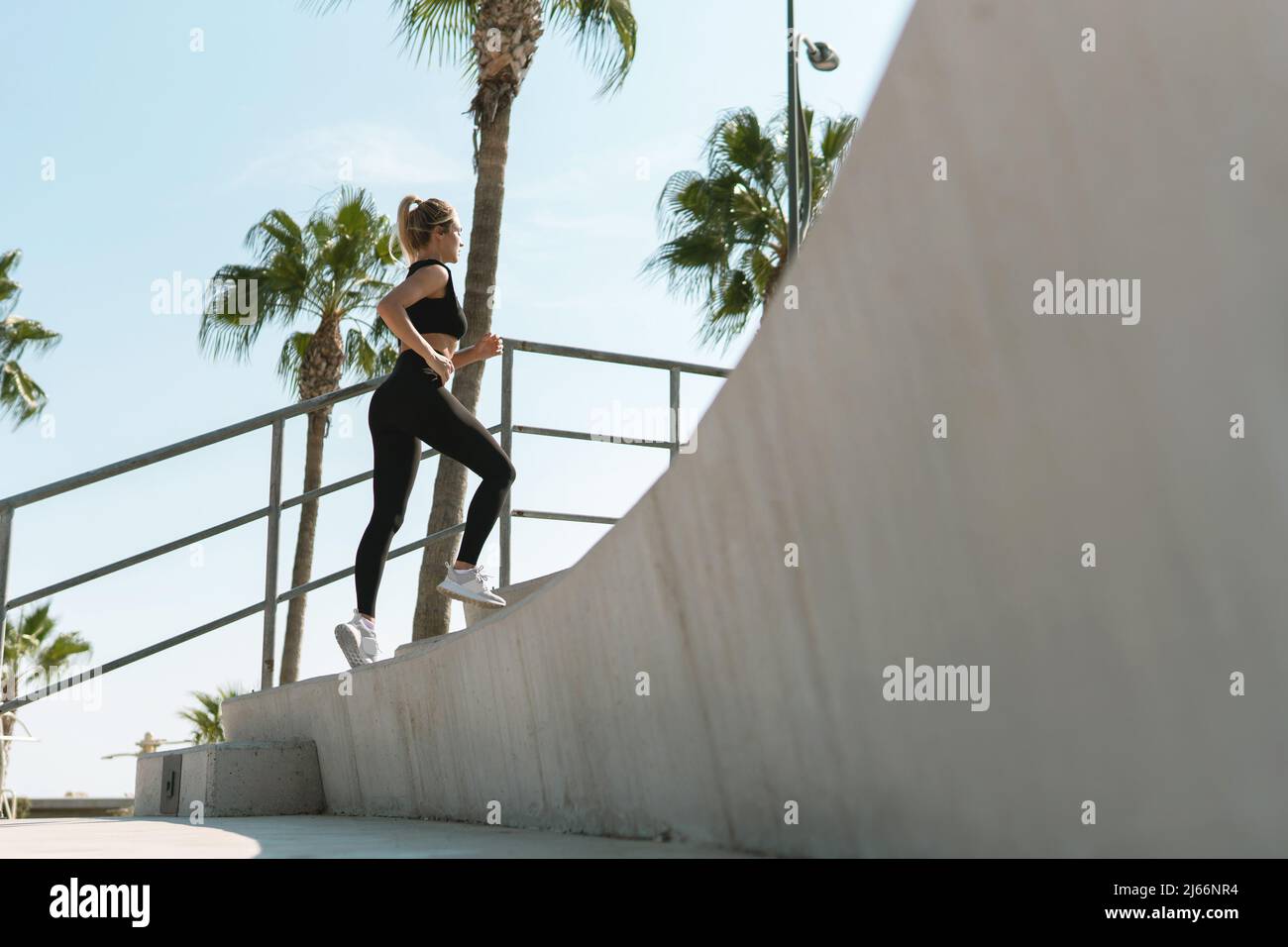 Young athletic woman is running on concrete stairs during her street
