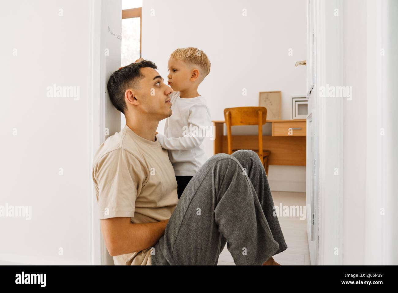 White boy drawing on doorjamb while measuring his father's height at home Stock Photo
