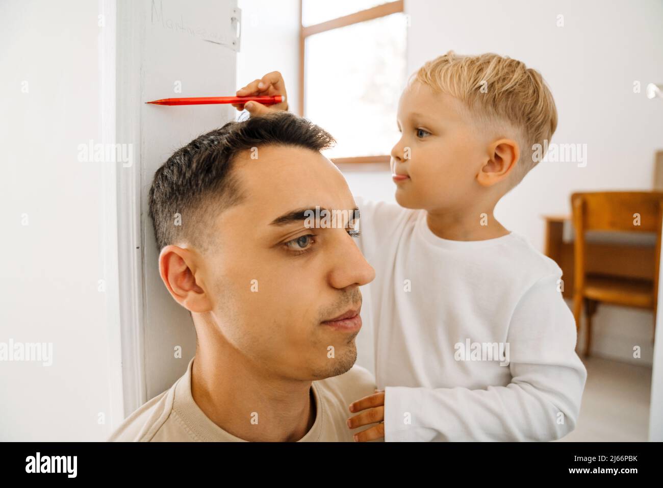White boy drawing on doorjamb while measuring his father's height at home Stock Photo
