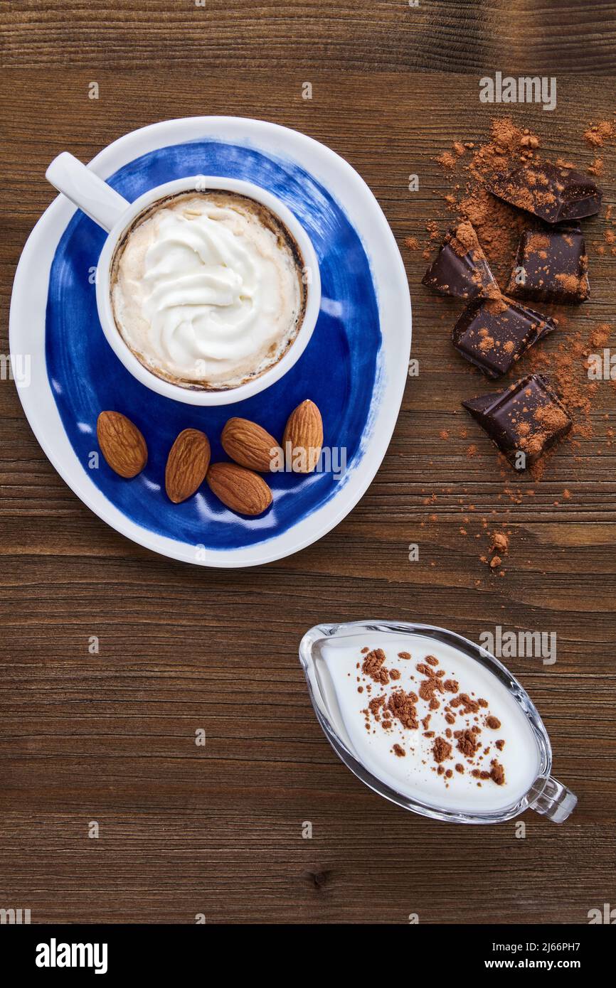 Blue cup of cappuccino almonds chocolate and milk in a glass milk jug Stock Photo