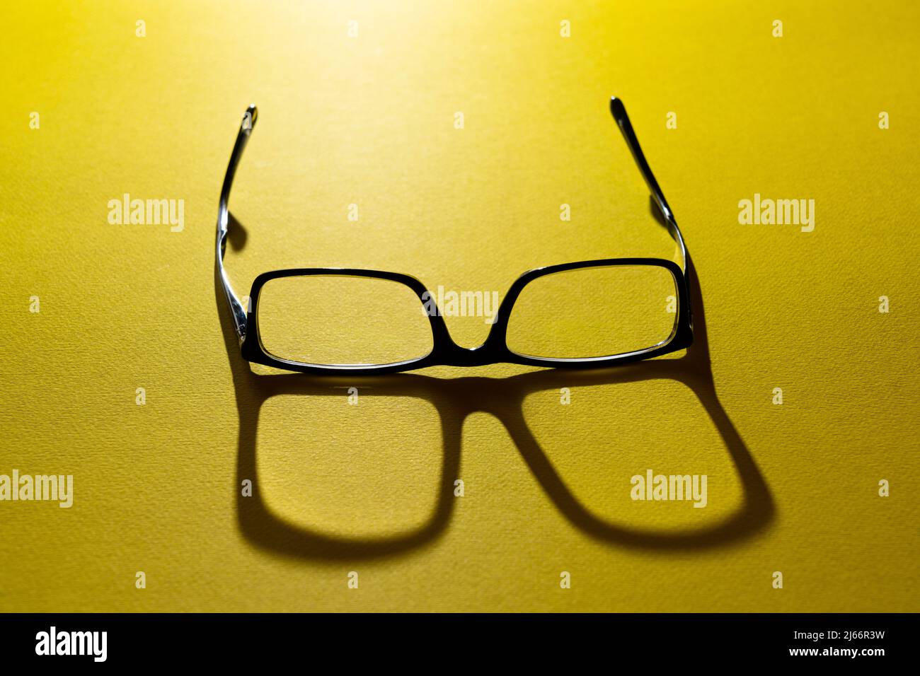 a pair of eyeglasses on a yellow surface Stock Photo