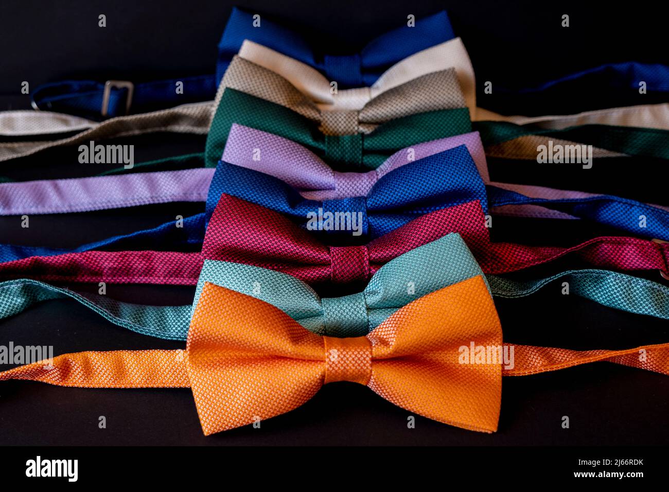 Colorful bow ties arranged in a row, man clothing accessory fashion concept, orange color necktie on the front, selective focus Stock Photo