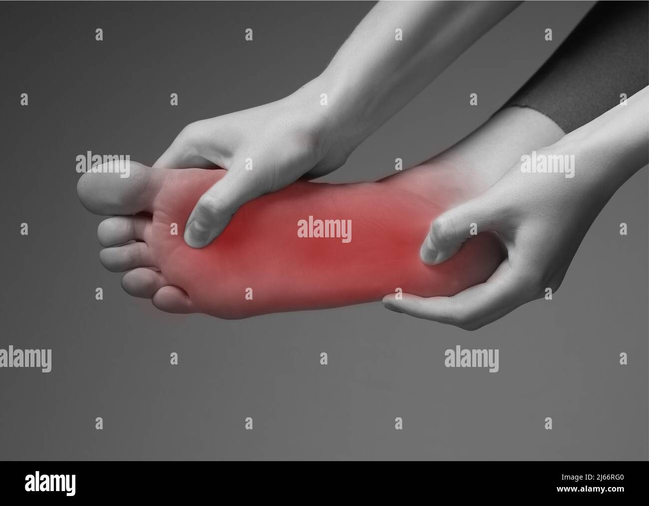 Foot pain. Woman hands holding leg with red point. Black and white. Inflammation, injury, chronic diseases consequences. Health problems concept. High quality photo Stock Photo