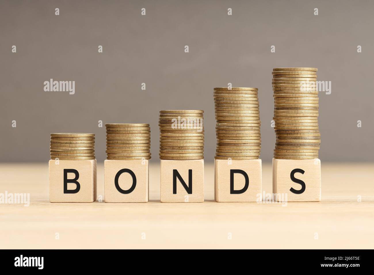 Bonds word in wooden blocks with coins stacked in increasing stacks. Bonds increasing concept. Copy space Stock Photo