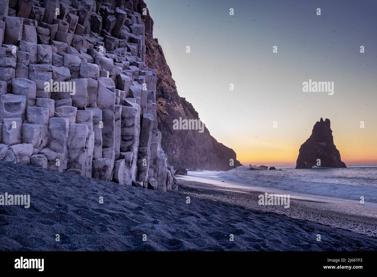 Schwarzer Strand Reynisfjara mit Basaltsäulen, Foto in der Morgendämmerung aufgenommen. Im Hintergrund einer der Reynisdrangar-Felsen. Stock Photo