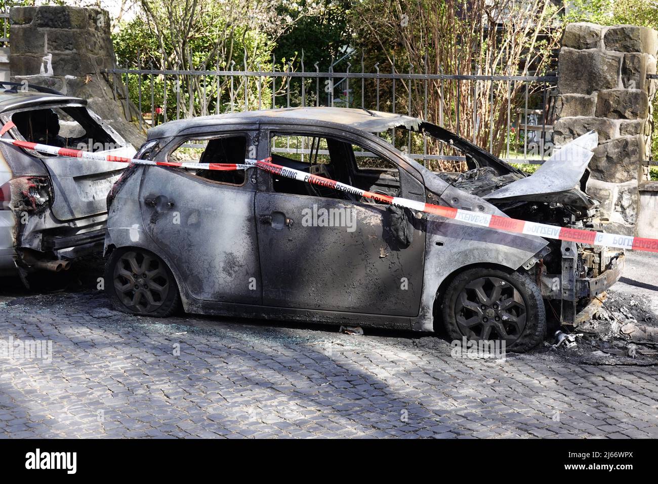 burnt out car wrecks behind police tape in residential street in Germany Stock Photo
