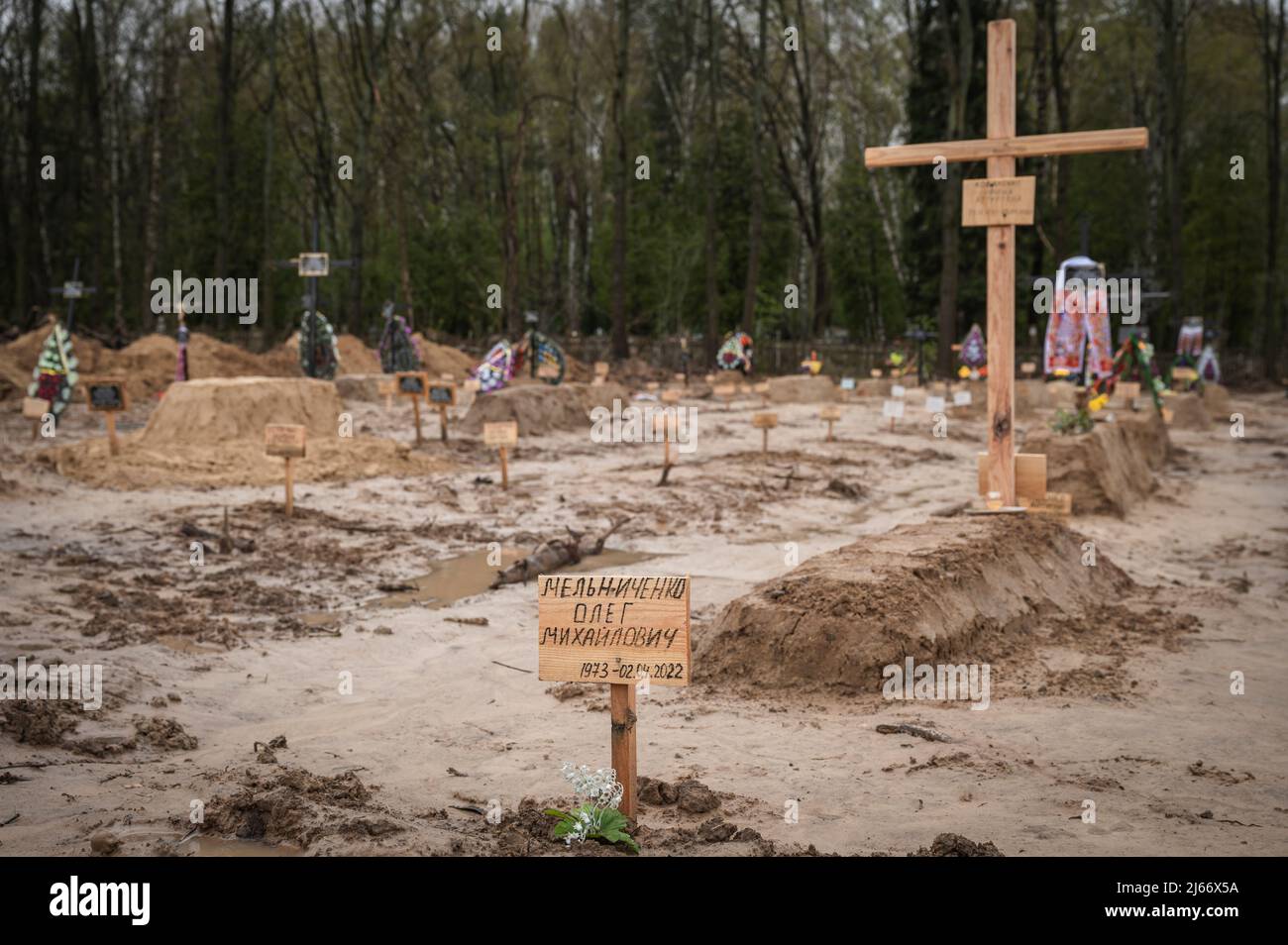 A cross seen on a new grave and signs with names of deceased people. A mass grave for bodies of