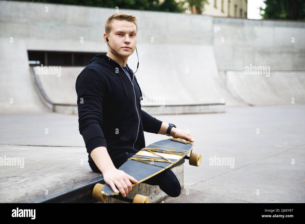 Young and motivated handicapped guy with a longboard in a skatepark