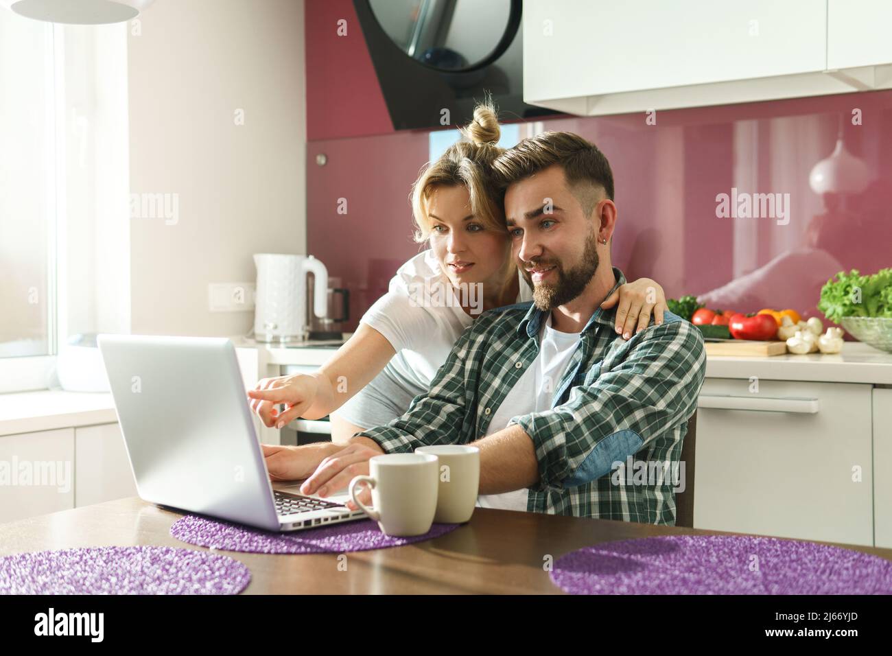 Happy couple using laptop in the kitchen at morning Stock Photo - Alamy