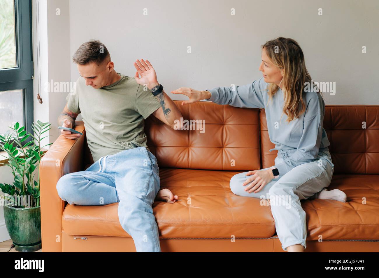 A man uses a mobile phone and ignores his wife who wants to talk about problems Stock Photo