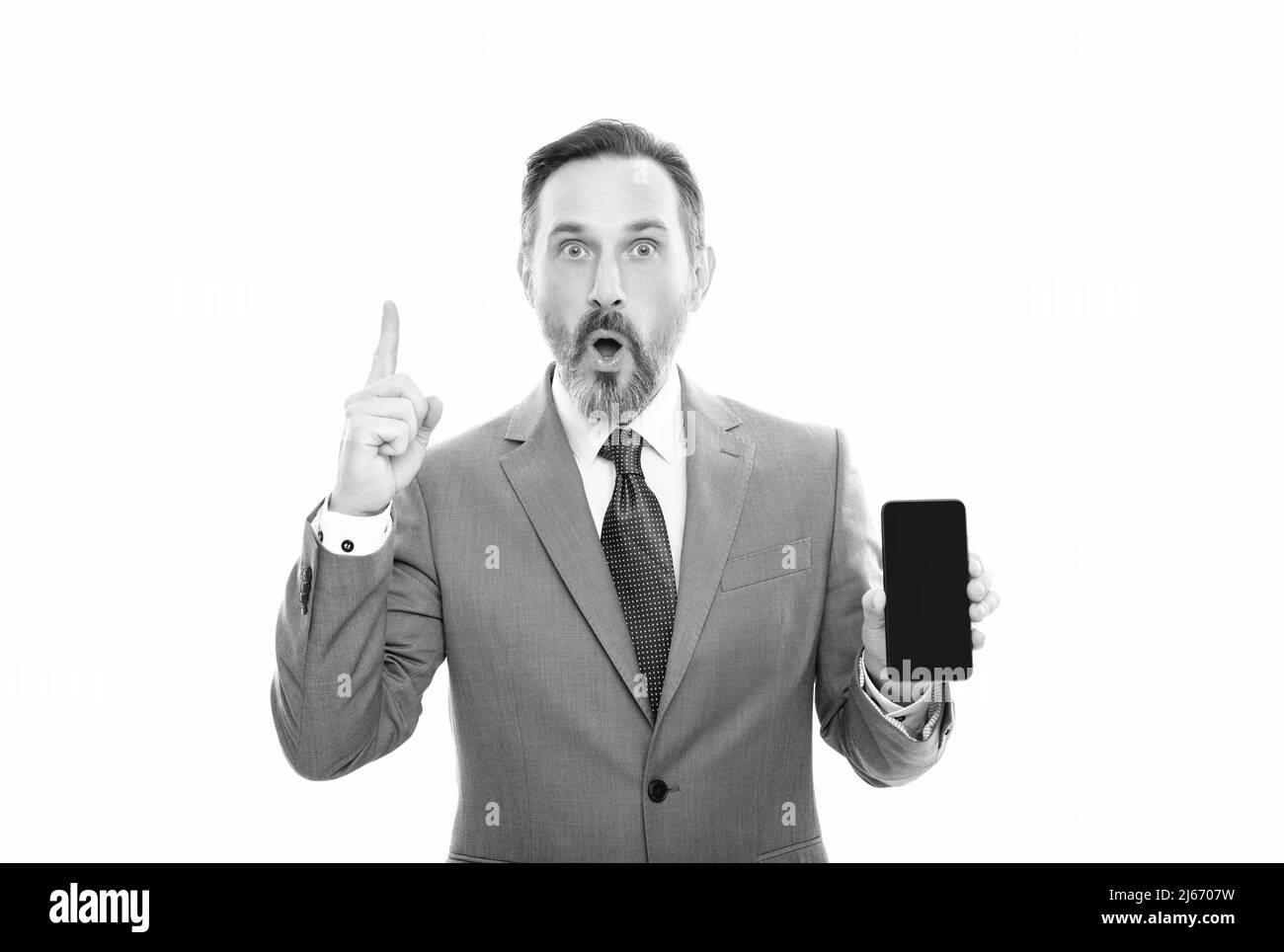 shocked businessman showing smartphone isolated on white. man in suit raised finger. Stock Photo