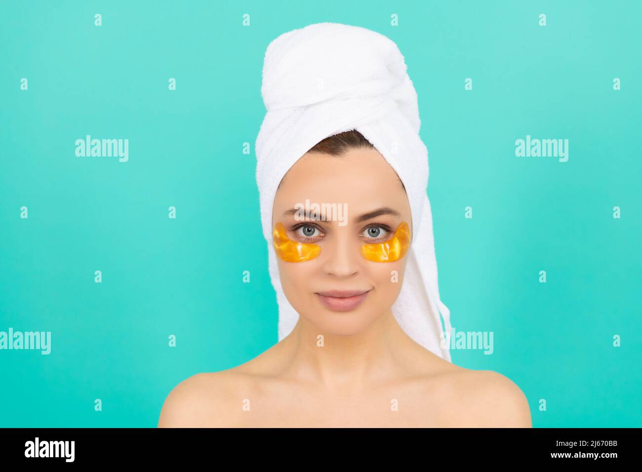 girl has collagen golden eye patches on face with towel Stock Photo