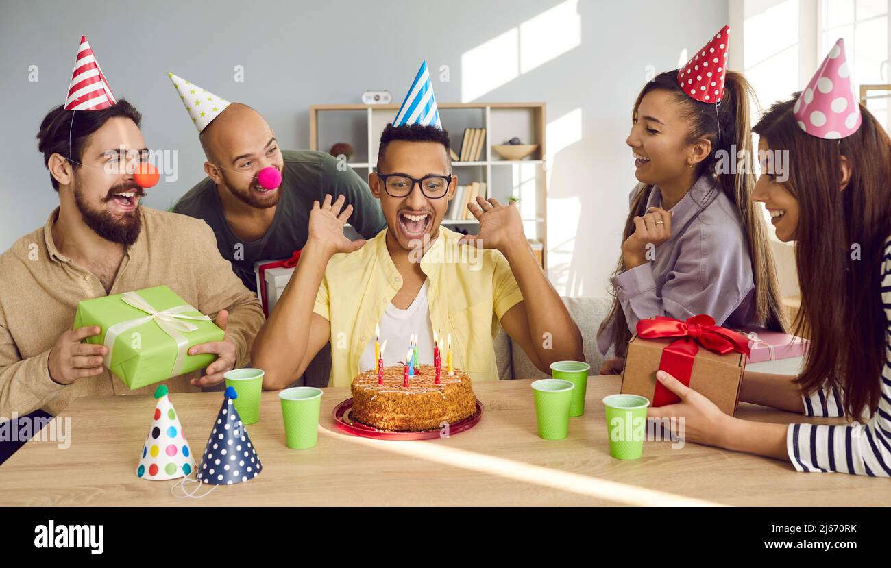 Smiling African American guy blow candles on birthday cake Stock Photo