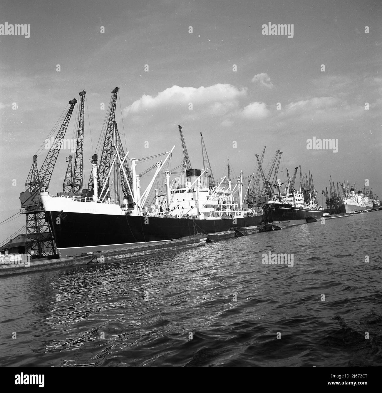1960s, historcial, Port of London, large steam drived cargo ships moored up beside the dockside cranes, East London docks, England, UK. Stock Photo