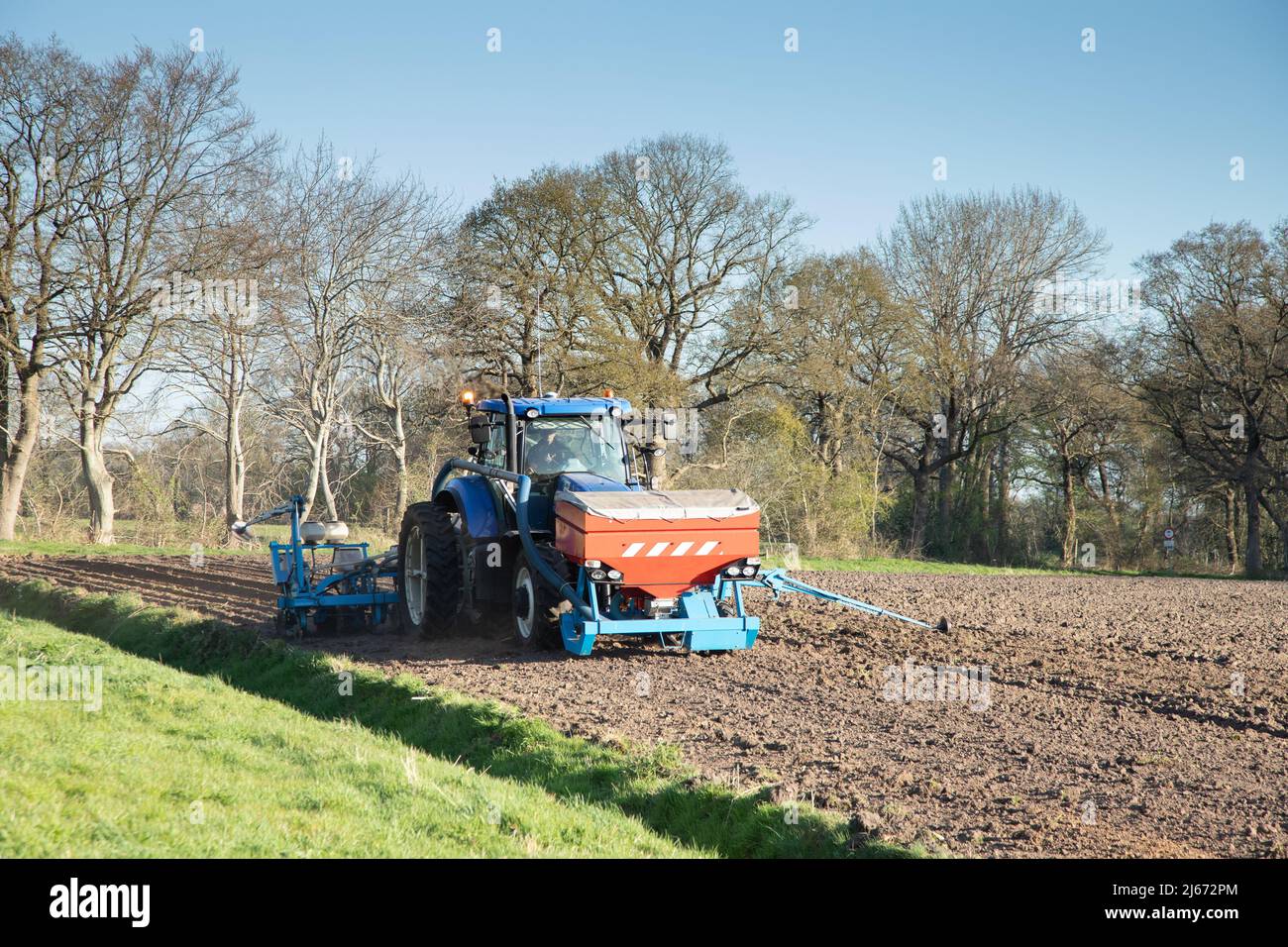 Close up of a tractor with an attached seed drill and fertilizer applicator for sowing maize in a manure prepared new maize field at Oldend in Anderen Stock Photo