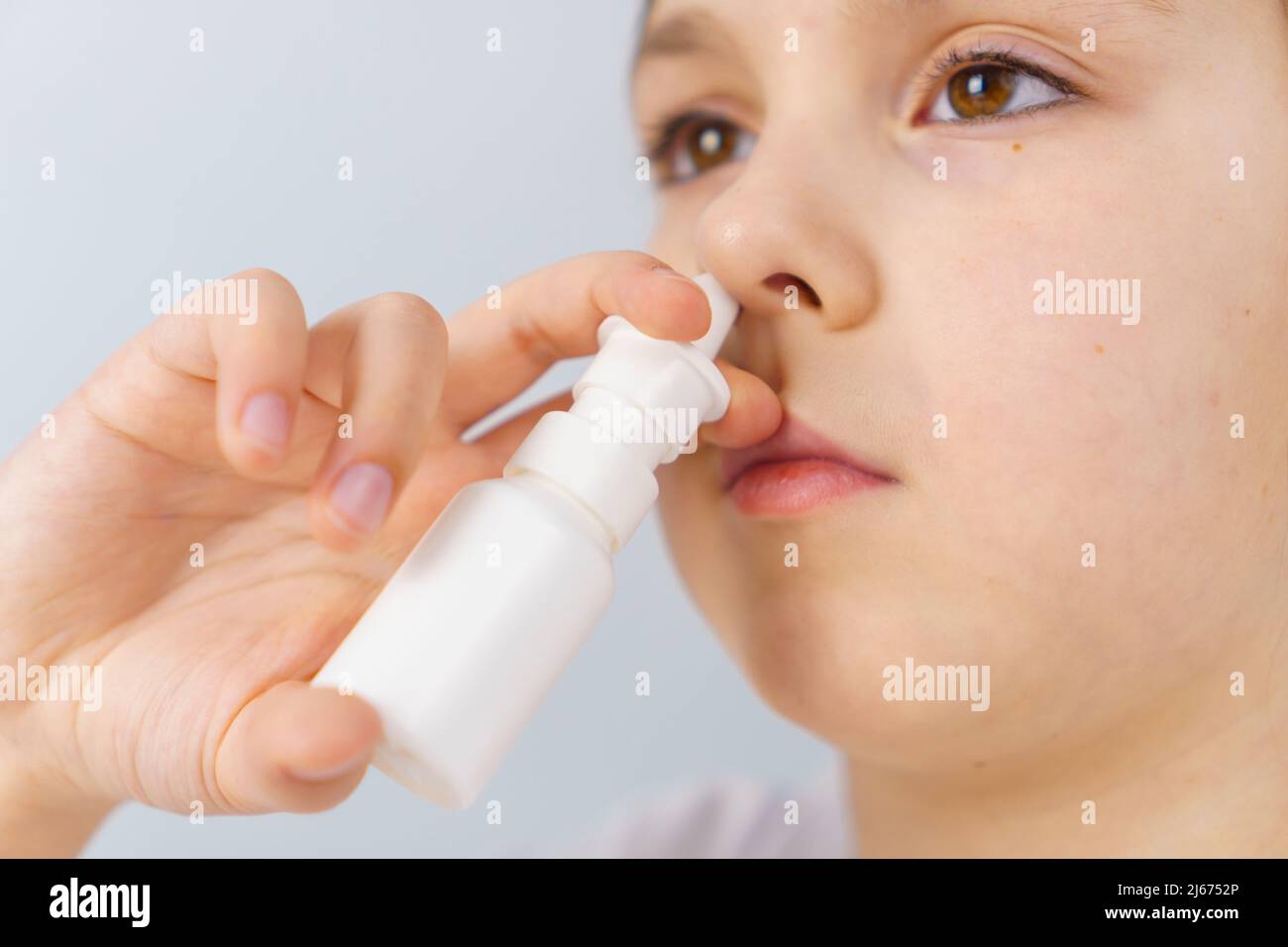 Little girl with runny nose does nasal spray irrigations to stop allergic rhinitis and sinusitis Stock Photo
