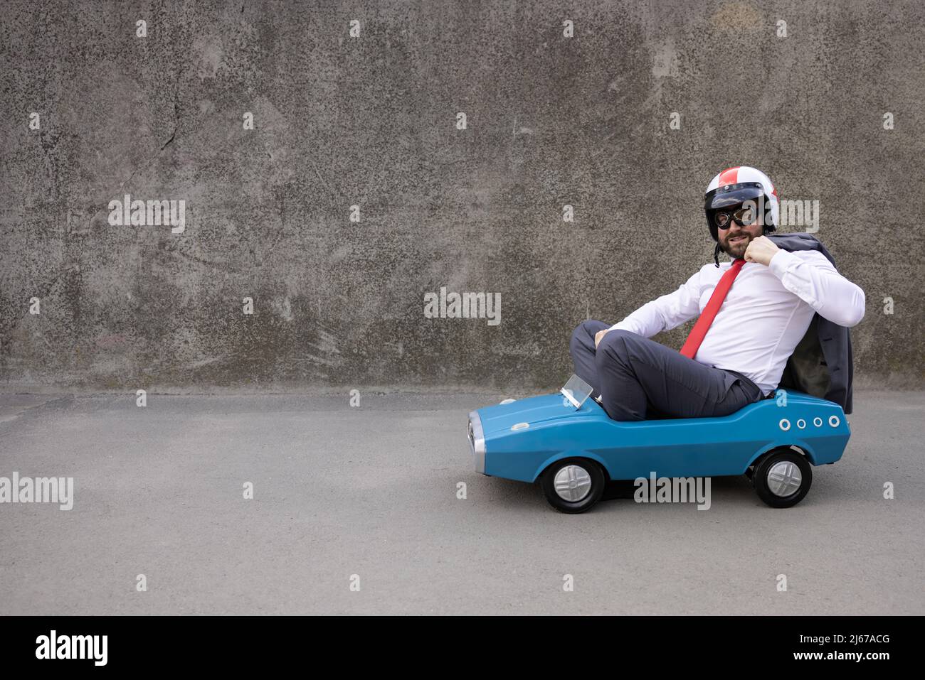 Portrait of funny businessman outdoor. Man driving retro pedal car ...