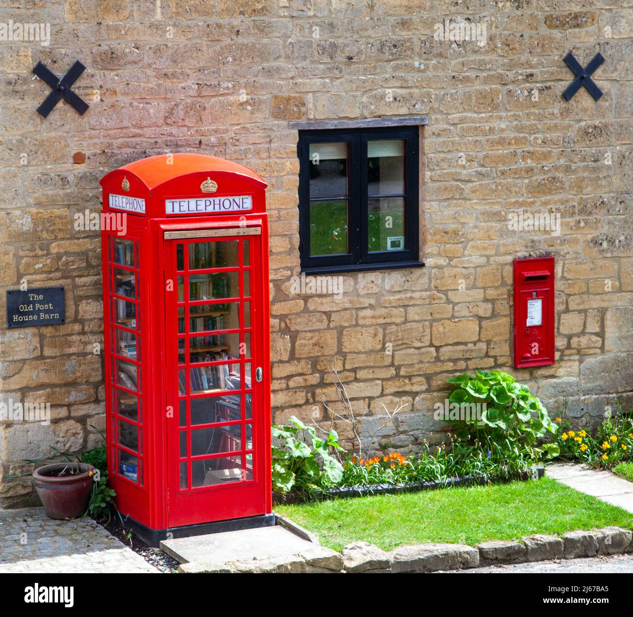 Red English post box and telephone kiosk now used as a book exchange in the village of Ashton under Hill Worcestershire Stock Photo