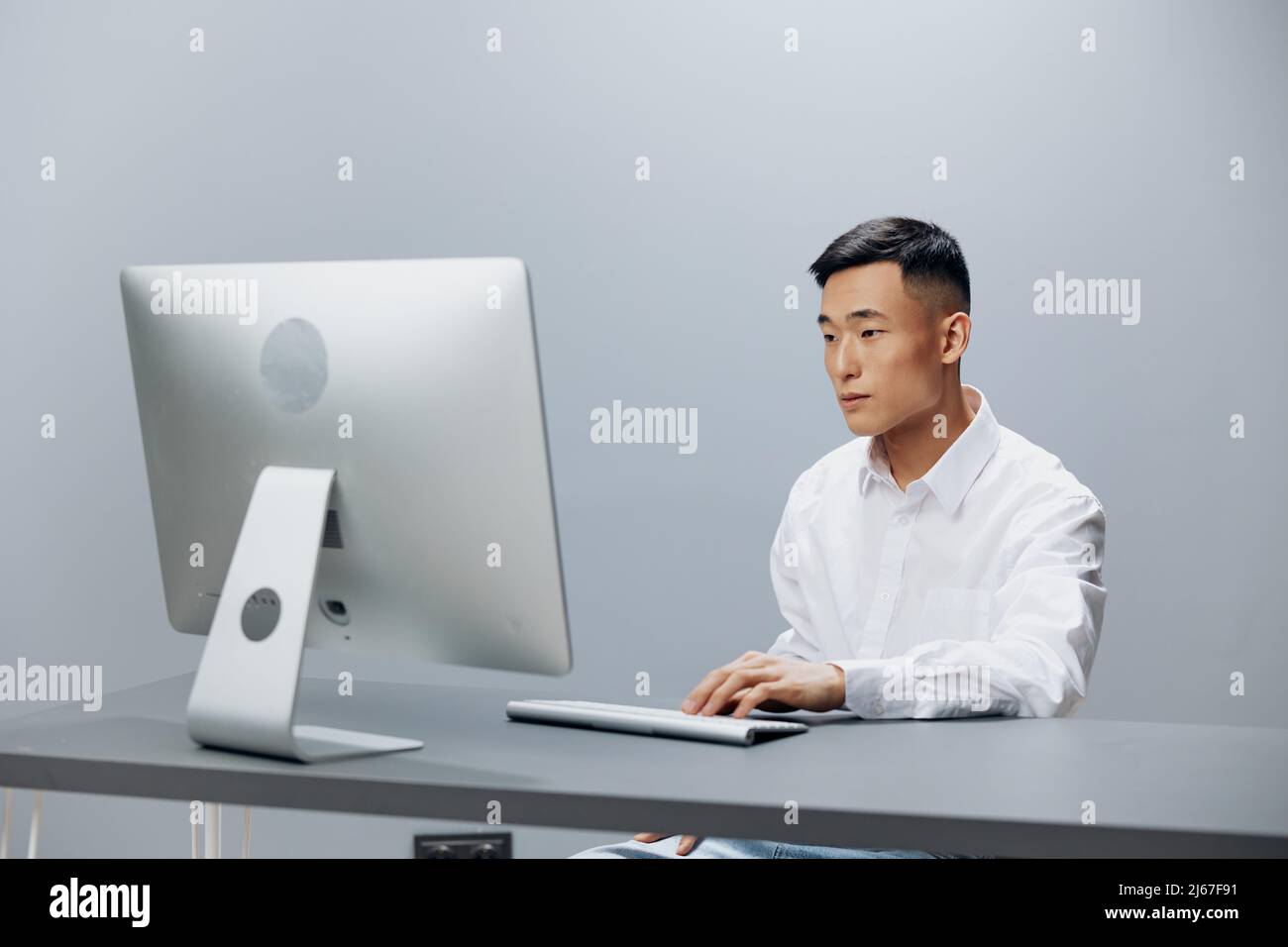 Asian man sit at a desk in front of a computer technologies Stock Photo ...