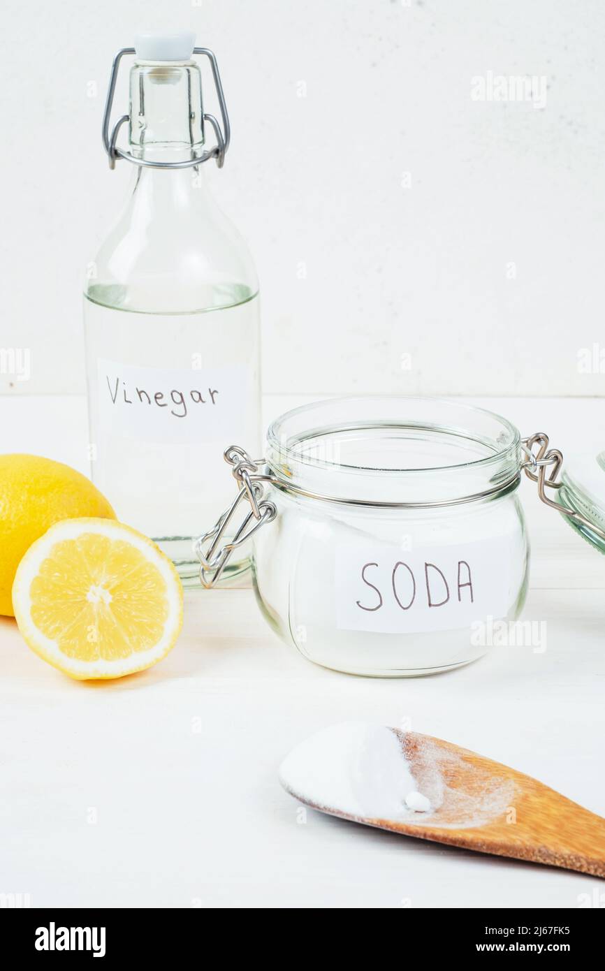 Baking soda in jar, vinegar, cut lemon, wooden spoon on a white background. The concept of removing stains on clothes. High quality photo Stock Photo