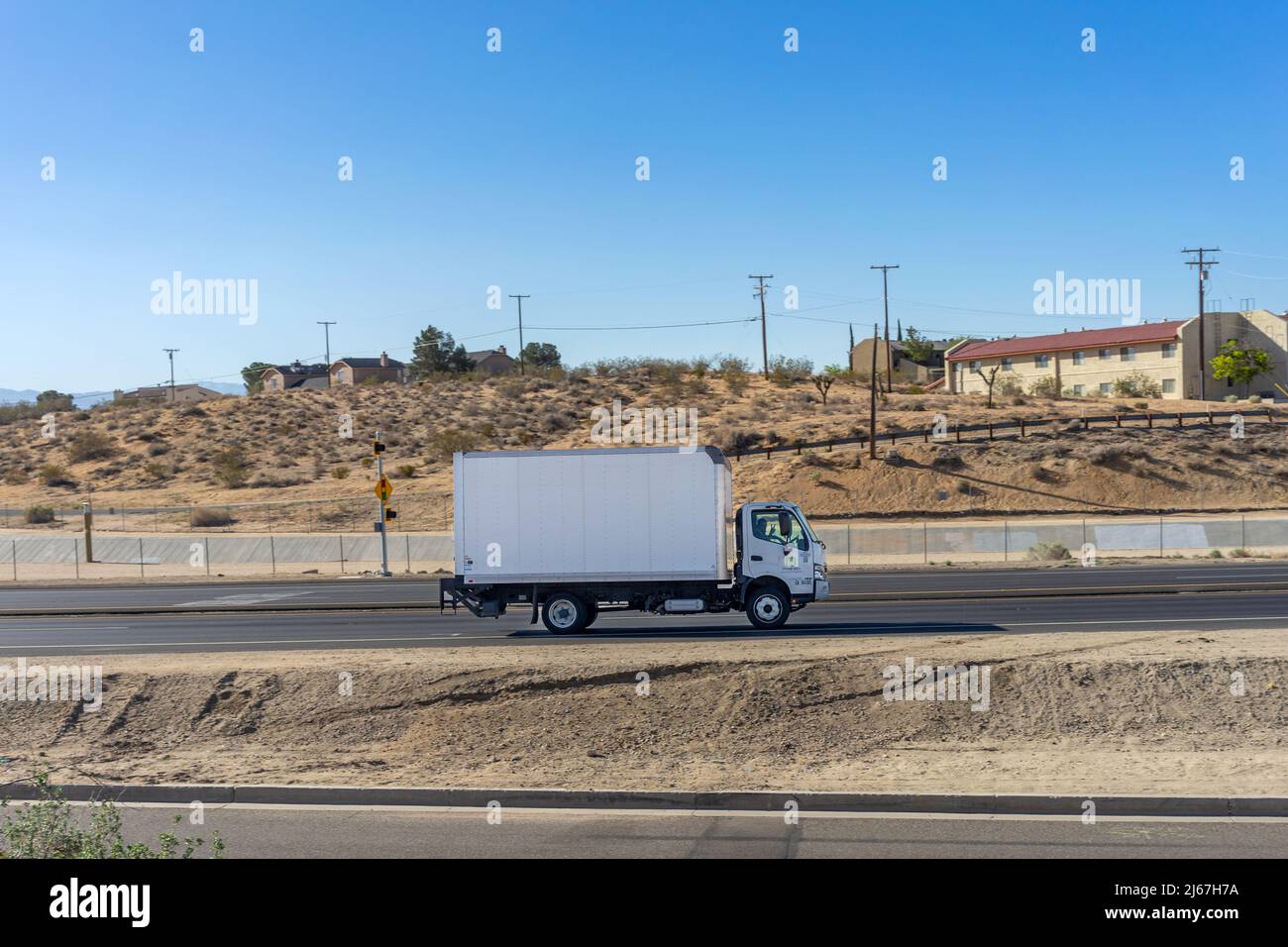 Apple Valley, CA, USA – April 20, 2022: A box truck travels on a highway in the Mojave Desert Town of Apple Valley, California. Stock Photo