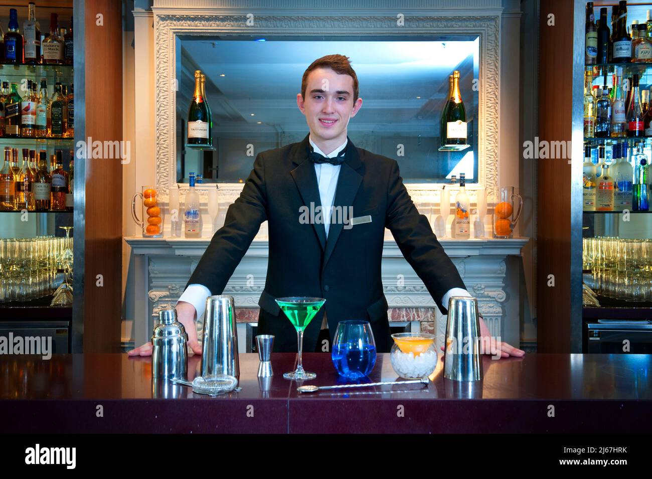 Bartender standing behind drinks at a bar counter of a luxury hotel Stock Photo