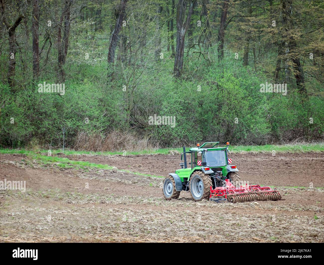 Aerial view of farm tractor harrowing arable field Stock Photo