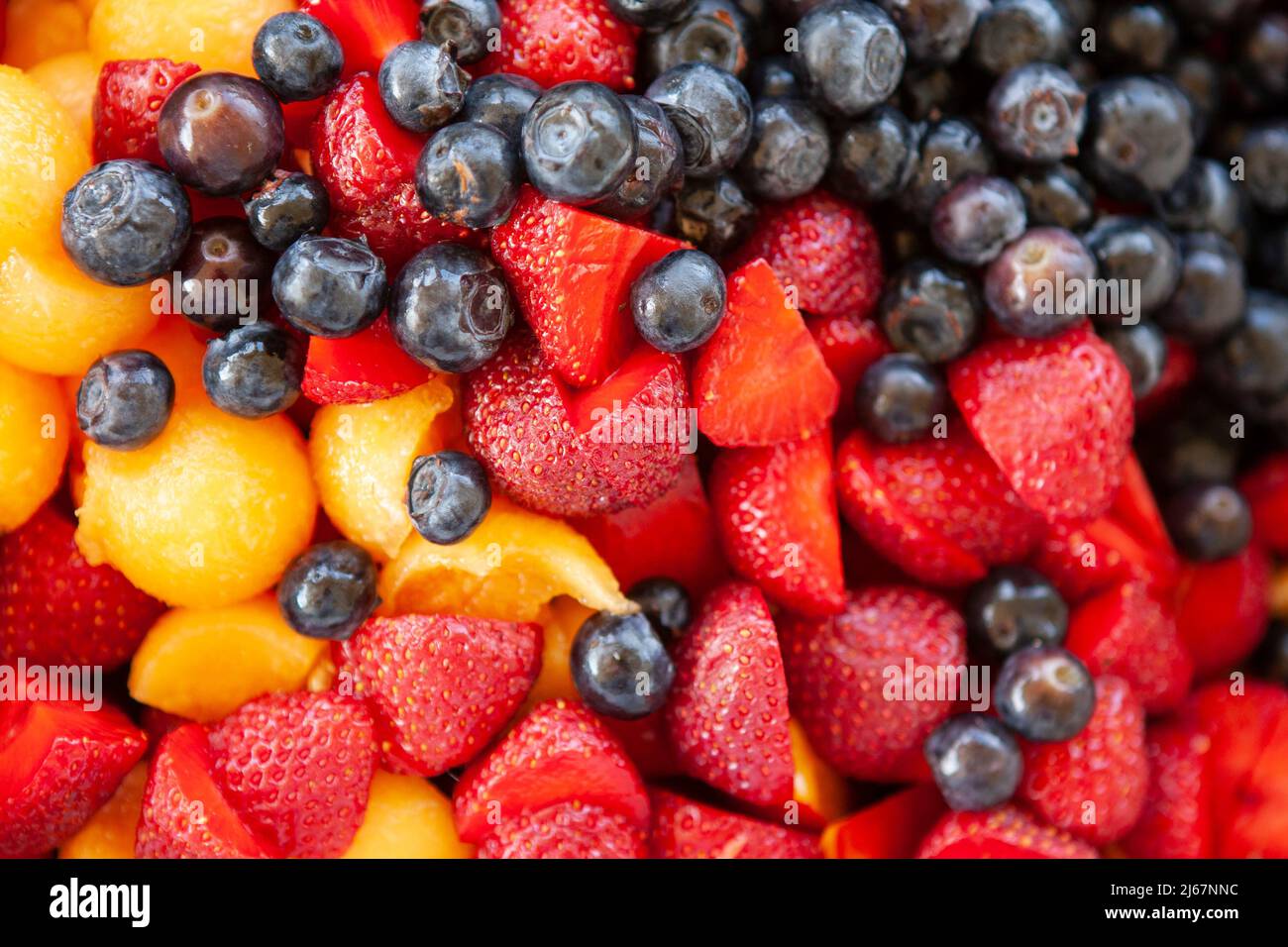 Closeup overhead view of a healthy fresh fruit salad, featuring blueberries, strawberries, and cantaloupe, providing a refreshing summer treat. Stock Photo