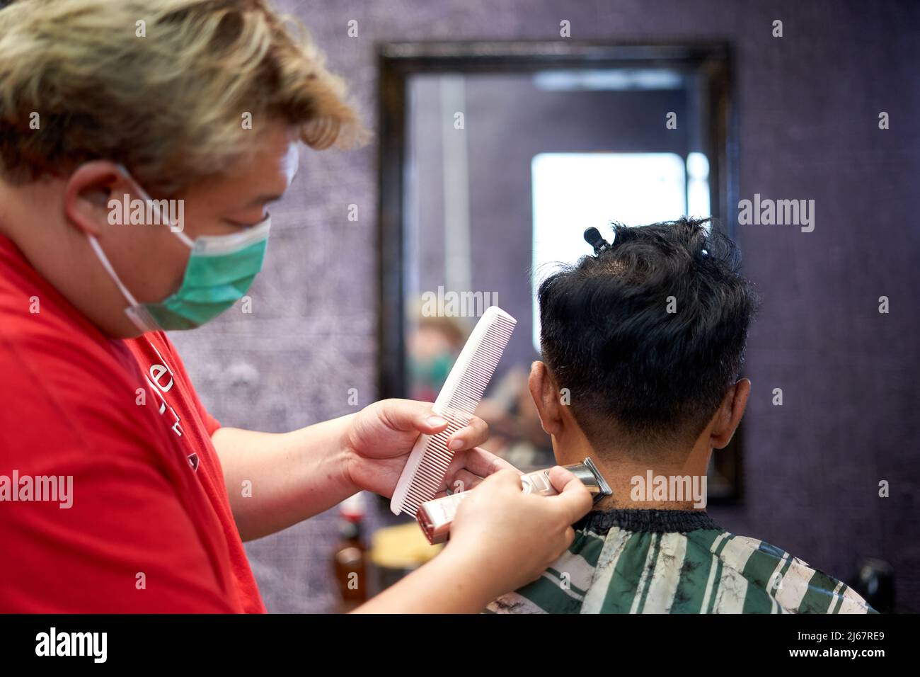 Barber shaving the nape of a client using a clipper and comb Stock Photo