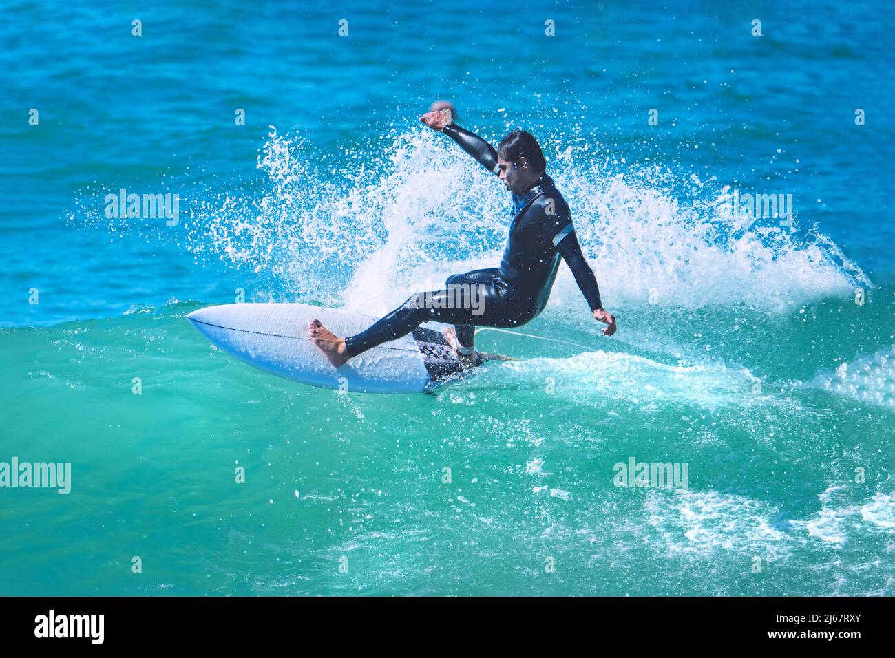 Surfer riding the wave on shortboard. Man catching waves in ocean. Water sports activity Stock Photo