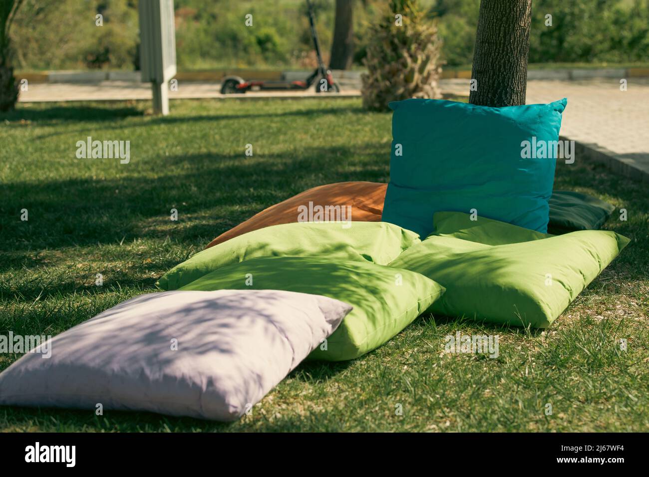 Students sitting on cushions under trees Stock Photo Alamy
