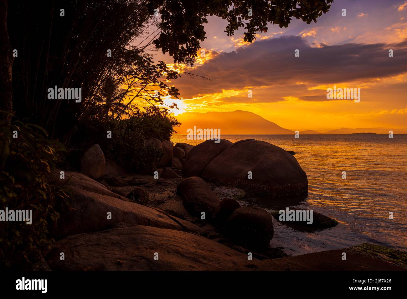 Amazing sunset on beach with big stones and quiet ocean in Florianopolis, Brazil Stock Photo